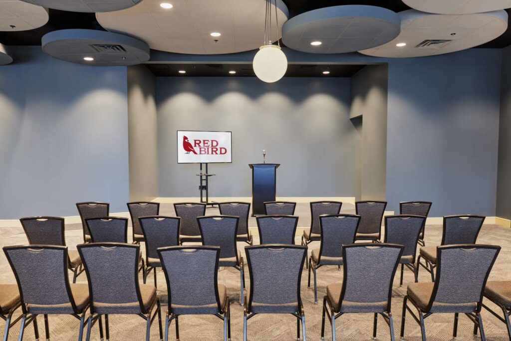 a room with a podium, chairs, and a red bird sign