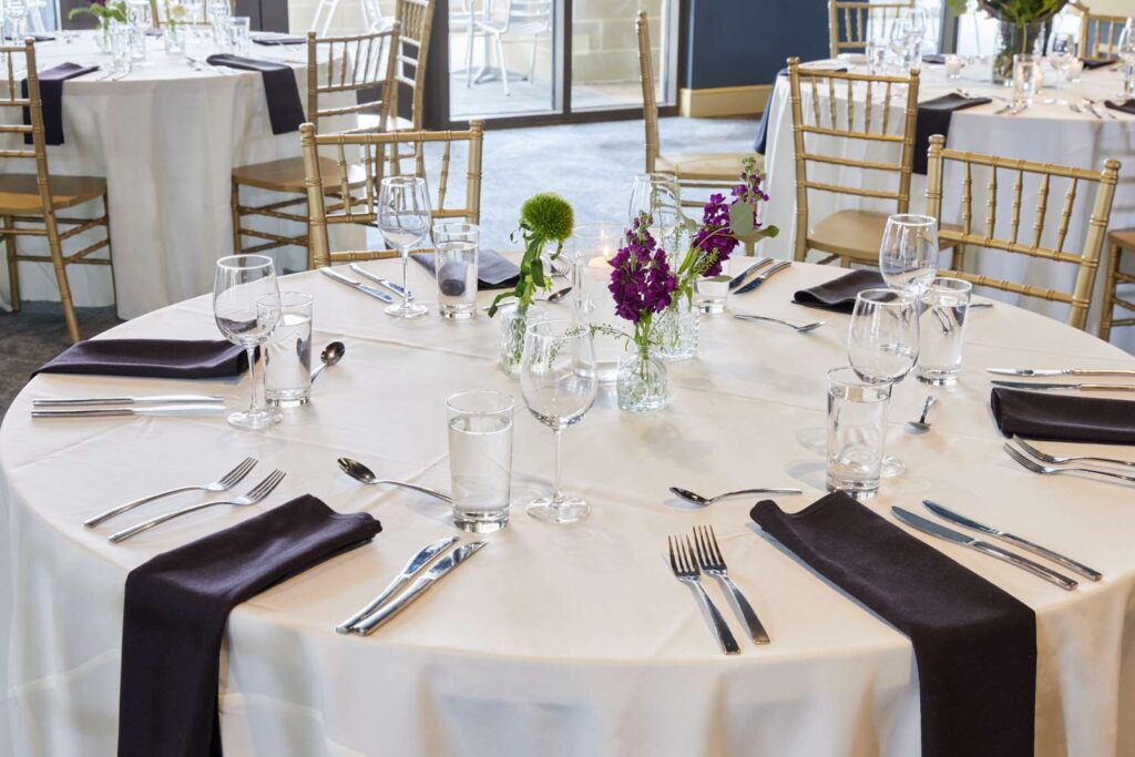 a table set for a formal dinner with purple flowers