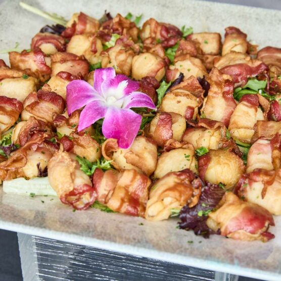 a plate of bacon-wrapped nibbles garnished with a flower