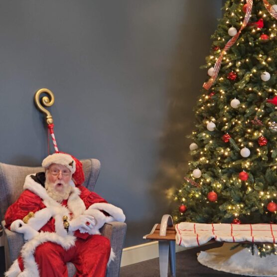 santa sitting next to a decorated tree